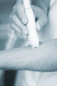 Close-up of doctor applying medicine on patient arm in hospital