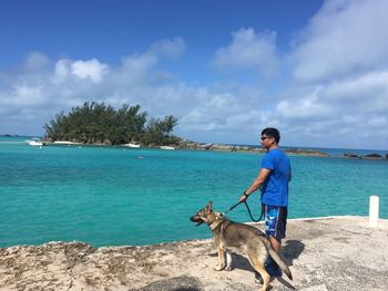 Dog standing on beach against cloudy sky