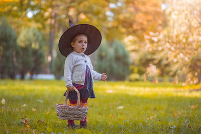 Full length of cute baby girl in basket on field