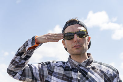 Man saluting against sky