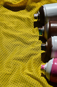 High angle view of aerosol cans on yellow textile