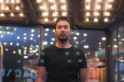 Portrait of young man standing in illuminated room