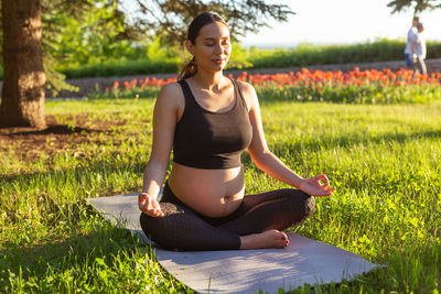 Full length of pregnant woman meditating at park