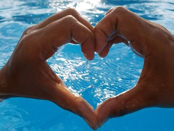 Close-up of hands heart shape in swimming pool