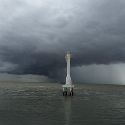 Lighthouse in sea against sky