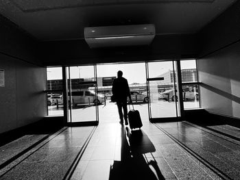 Rear view of man walking with luggage at airport