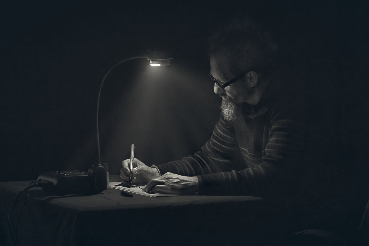 dark, one person, lighting equipment, indoors, eyeglasses, table, illuminated, night, studio shot, sitting, technology, young women, young adult, black background, close-up, people