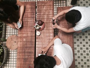 High angle view of friends using phones at table