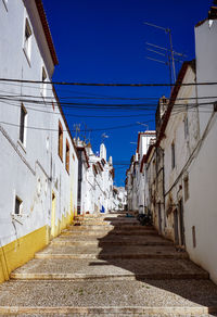 Narrow alley amidst buildings against blue sky