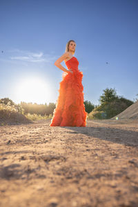 Portrait of young woman standing at beach against sky