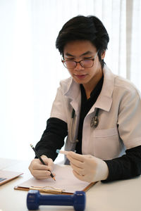 Mid section of a man with eyeglasses on table