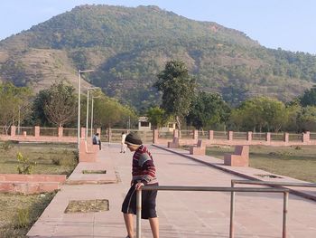 Rear view of woman walking on mountain against sky