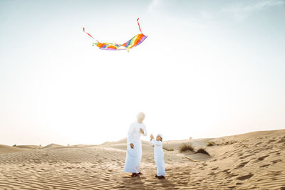 Rear view of people on beach against clear sky