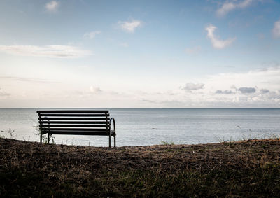 Empty bench on shore at beach