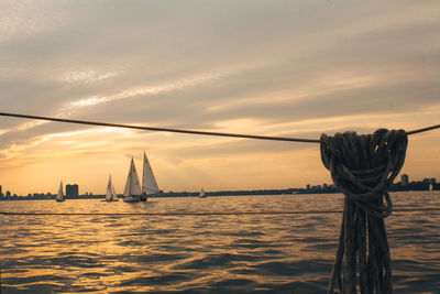 Sailboats in sea against sky during sunset