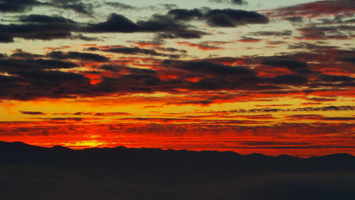 Scenic view of mountains against cloudy sky at sunset