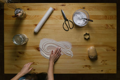 Top view of a young woman making christmas cookies on a wooden table