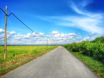 Road amidst field against sky