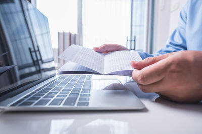 Midsection of man reading book on table