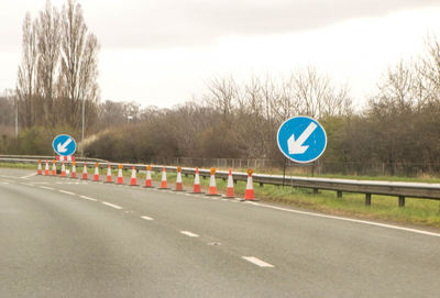 Road sign by highway against sky