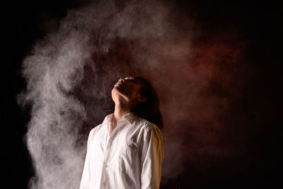 Woman looking away against black background