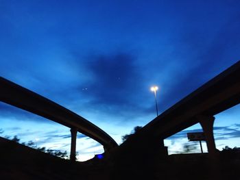 Low angle view of silhouette bridge against blue sky at night