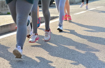 Low section of people walking on street in city