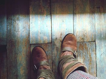 Low section of woman wearing boots on wooden floor