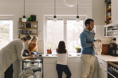 Family of four working in kitchen at home