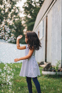 Diverse mixed race pre school age girl at home having fun playing with bubbles 