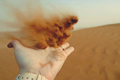 Close-up of hand throwing sand