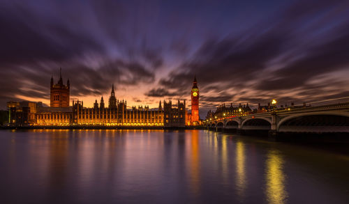 Westminster bridge over thames river against houses of parliament at night