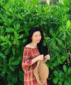 Portrait of young woman standing against plants