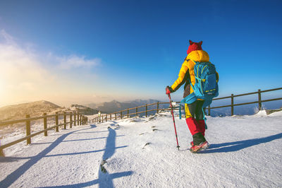 Person hiking on field against mountain during winter