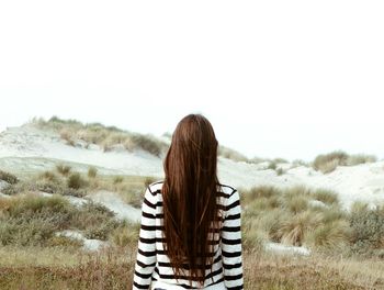 Woman standing on beach against clear sky