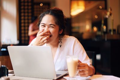 Mid adult woman using mobile phone in cafe