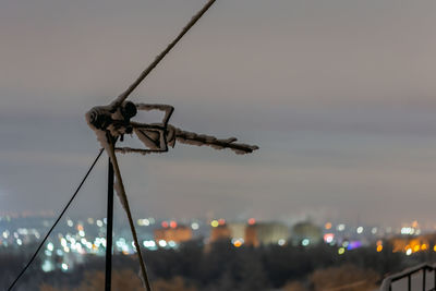 Frozen antenna on winter night roof over blurry city