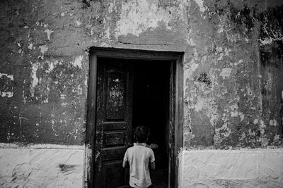 Rear view of man standing by window of old building