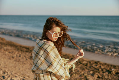 Side view of woman standing at beach against sky