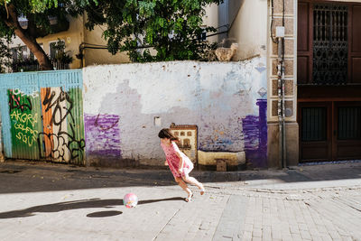 Young girl playing football/soccer in a colorful street