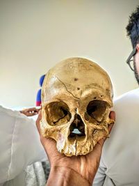 Close-up of human hand holding skull