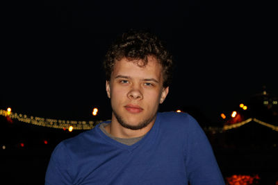 Portrait of young man against illuminated sky at night