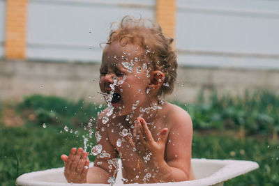 Cute shirtless girl splashing water outdoors