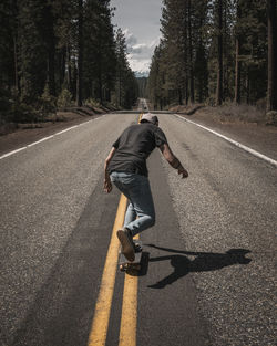 Rear view of man skateboarding on road