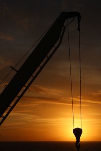 Low angle view of electricity pylon against sky during sunset