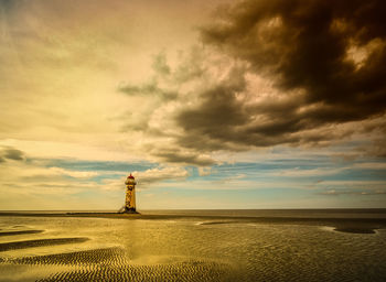 Point of ayr lighthouse at talacre beach against cloudy sky during sunset