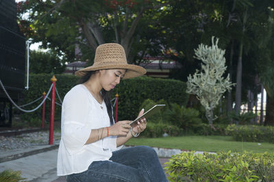 Woman using digital tablet while sitting at park