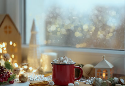 Cozy home christmas atmosphere, window view mug of hot chocolate on windowsill, evening at home