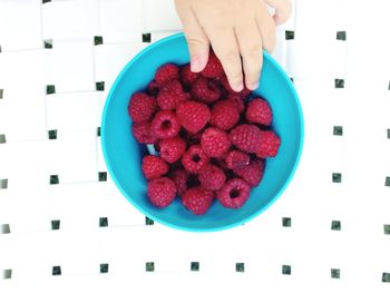 Close-up of hand holding strawberries in bowl