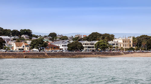 Houses by sea against sky in city